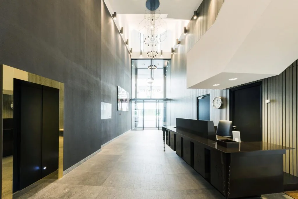 Moderne entreehal van een kantoorgebouw aan de Grote Markstraat met balie, lift en glazen schuifdeuren.